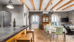 Cozinha moderna com parede de pedra, vigas de madeira e área de jantar com vista.