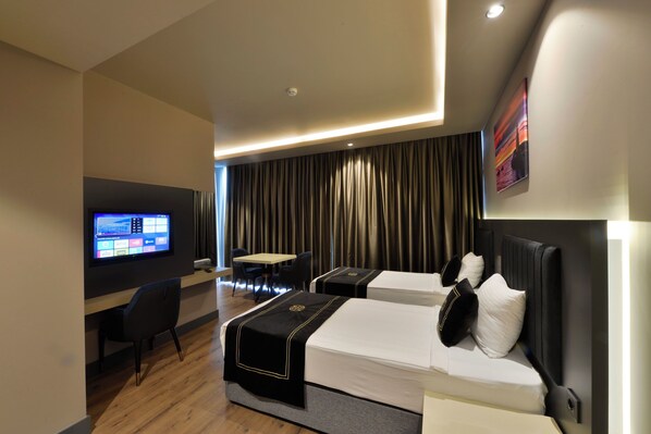 Een hotelkamer met twee bedden, een bureau, een televisie en uitzicht op gordijnen.