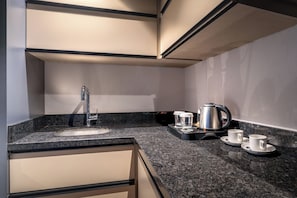 Cozinha moderna com bancada de granito, pia de aço inoxidável e chaleira.