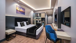 A modern hotel room with a bed, bedside tables, a desk, a chair, a large mirror, and a painting on the wall. - Best Western Premier Hidden Hills (Arnavutköy)