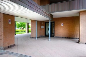 A covered outdoor area with brick walls and a tiled floor, featuring a no parking sign and a door. - UR-NEST Fantin, Modern and bright one-bedroom apartment  (Bologna)