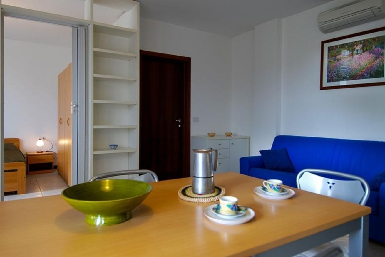 Ein kompakter Wohnbereich mit Essplatz, einem blauen Sofa und einer Küchenzeile.