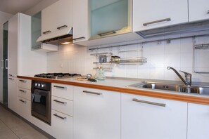 A modern kitchen with white cabinets, stainless steel appliances, and a wooden countertop.