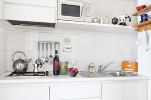 A kitchen with white cabinets, a microwave, a kettle, a sink, and various kitchen utensils. - UR-NEST Marconi 7, Bright and modern one bedroom apartment (Bologna)