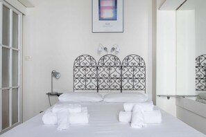 A hotel room with a bed, white linens, a metal headboard, a bedside lamp, and a framed picture on the wall. - UR-NEST Marconi 7, Bright and modern one bedroom apartment (Bologna)