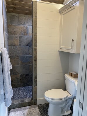 A bathroom with a stone shower enclosure, a white toilet, and a cabinet. - Couples Retreat Lakeside (Ingram)