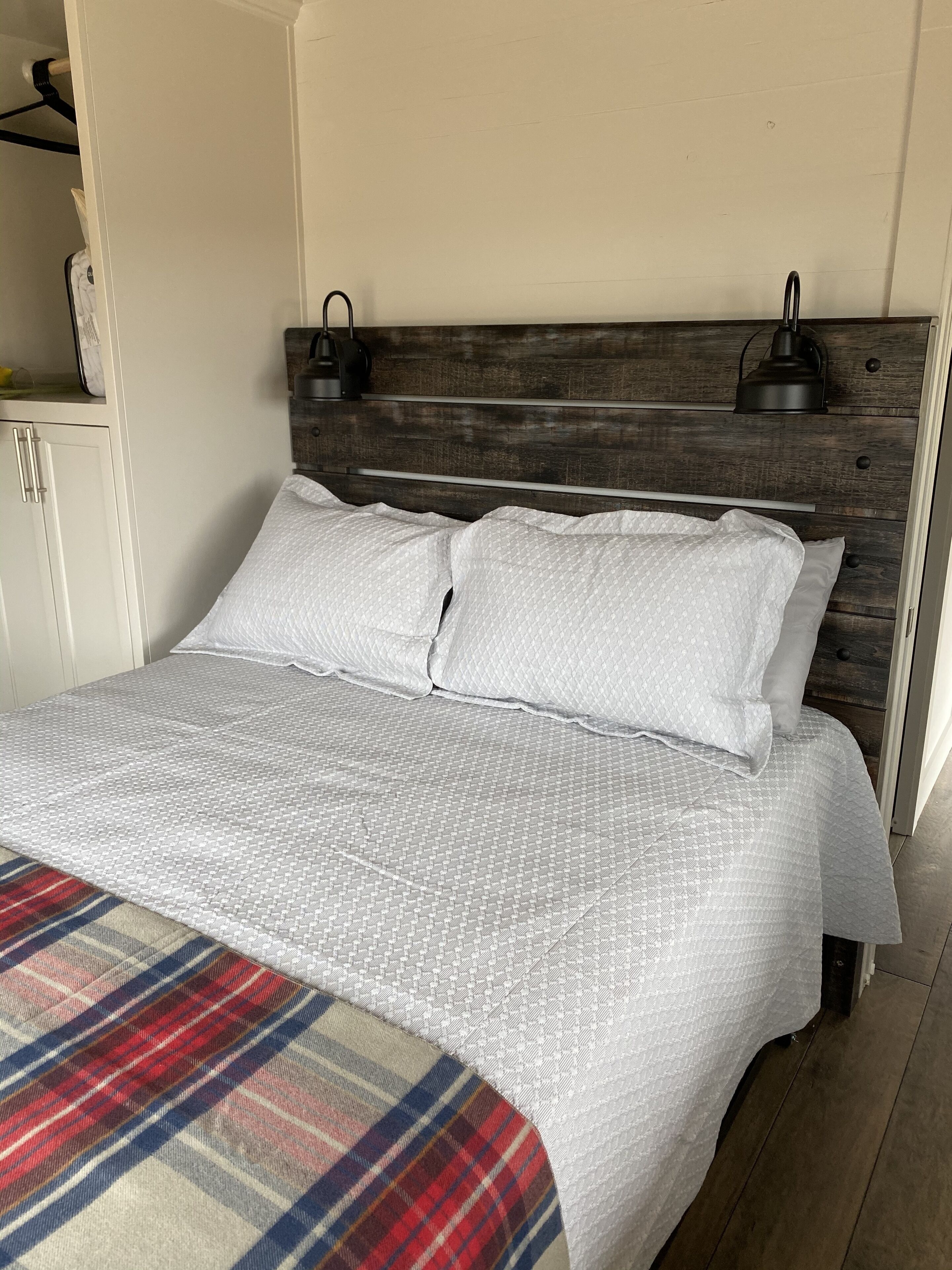 A bed with a plaid blanket, a wooden headboard, and two bedside lamps.