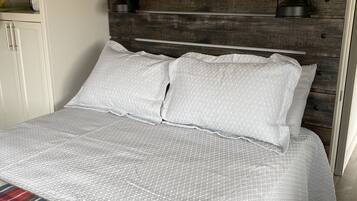 A bed with a plaid blanket, a wooden headboard, and two bedside lamps.