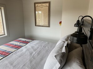 A bedroom with a bed, a headboard, a wall-mounted lamp, and a framed sign. - Couples Retreat Lakeside (Ingram)