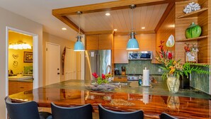 Een moderne keuken met een groot schiereiland, houten kastjes en hanglampen.