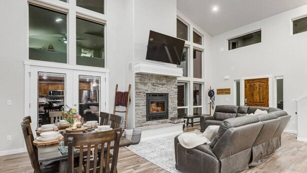A spacious living room with a fireplace, a dining area with a table and chairs, and a large gray sectional sofa.