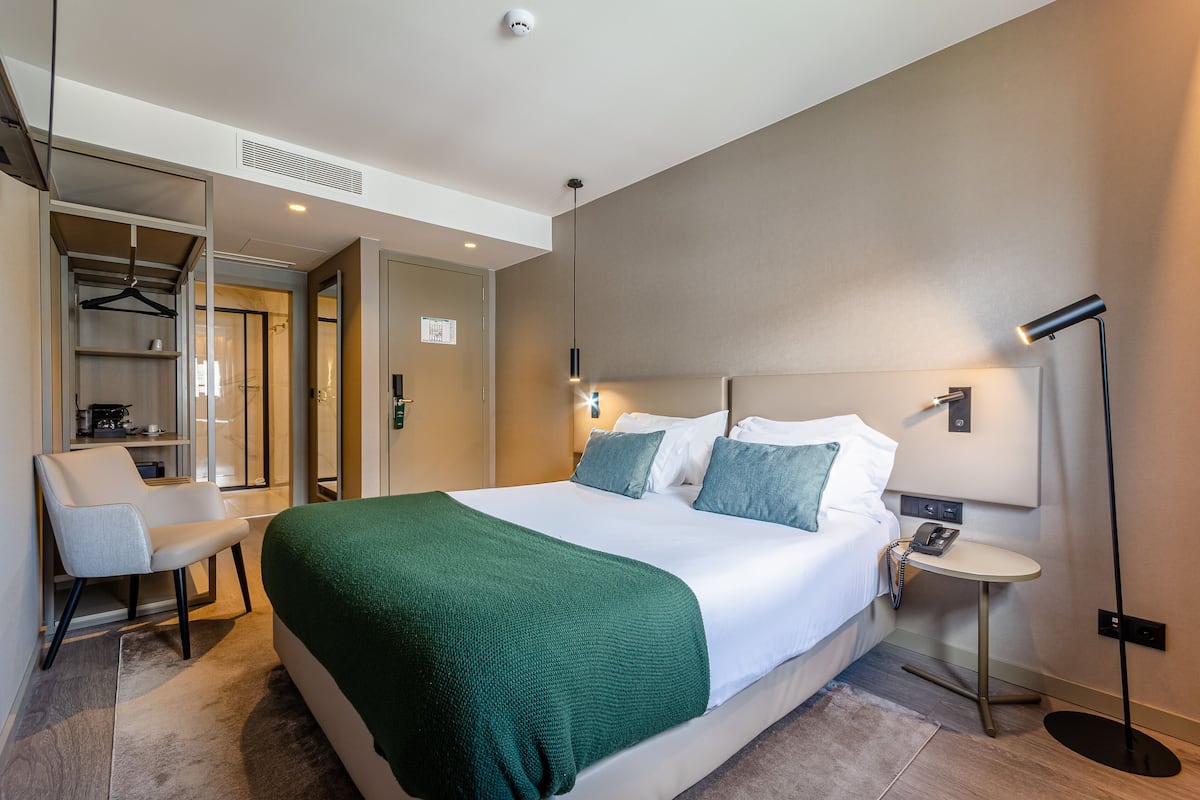 Ein Hotelzimmer mit Bett, Nachttisch, Lampe, Stuhl und begehbarem Kleiderschrank.