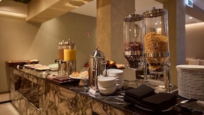 Un buffet proposant une variété de plats et d’accompagnements, notamment un distributeur de café et un distributeur de céréales.