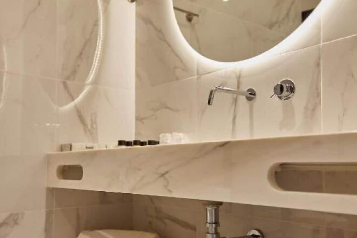 Ein Badezimmer mit Marmorwaschtisch, Waschbecken und Spiegel.