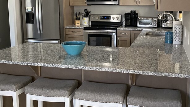 Una cocina moderna con electrodomésticos de acero inoxidable, encimera de granito y armarios de madera.