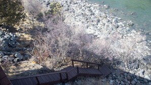 Una scala di legno che conduce a una spiaggia rocciosa con vegetazione rada.