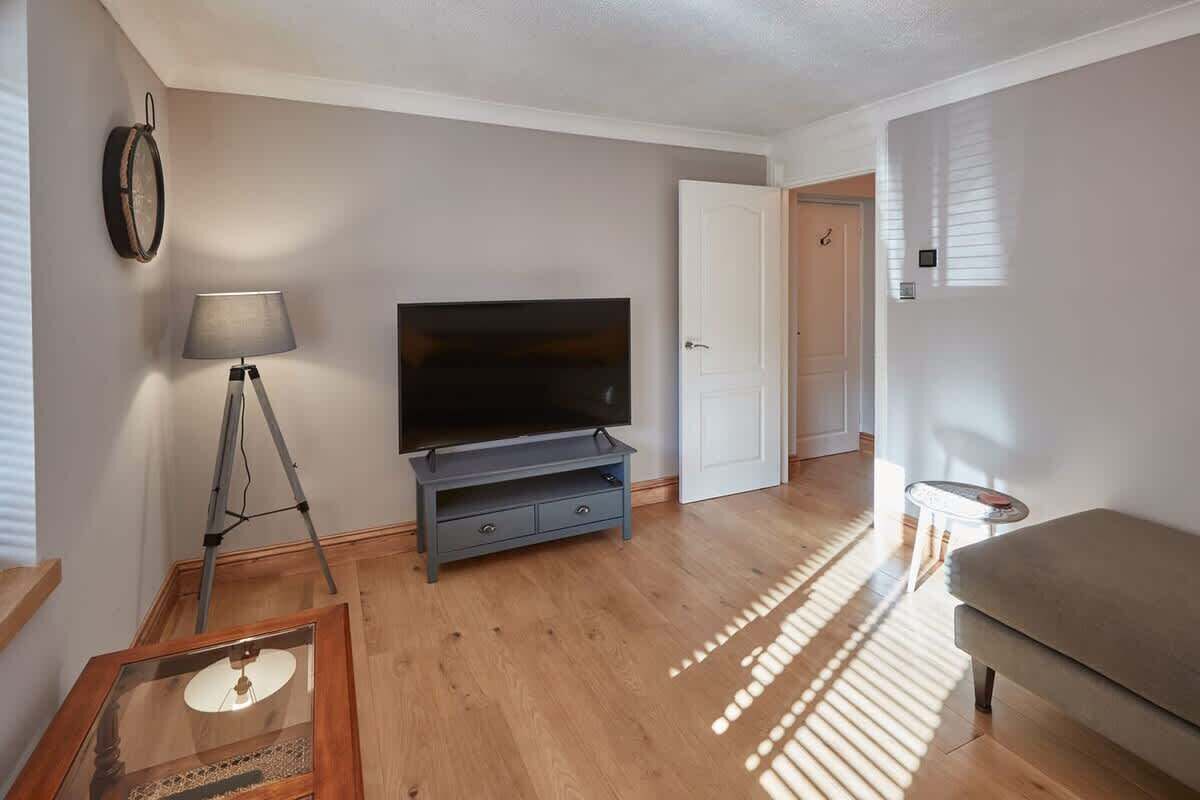 Una sala de estar con una televisión de pantalla plana sobre un mueble, una lámpara y un sofá.