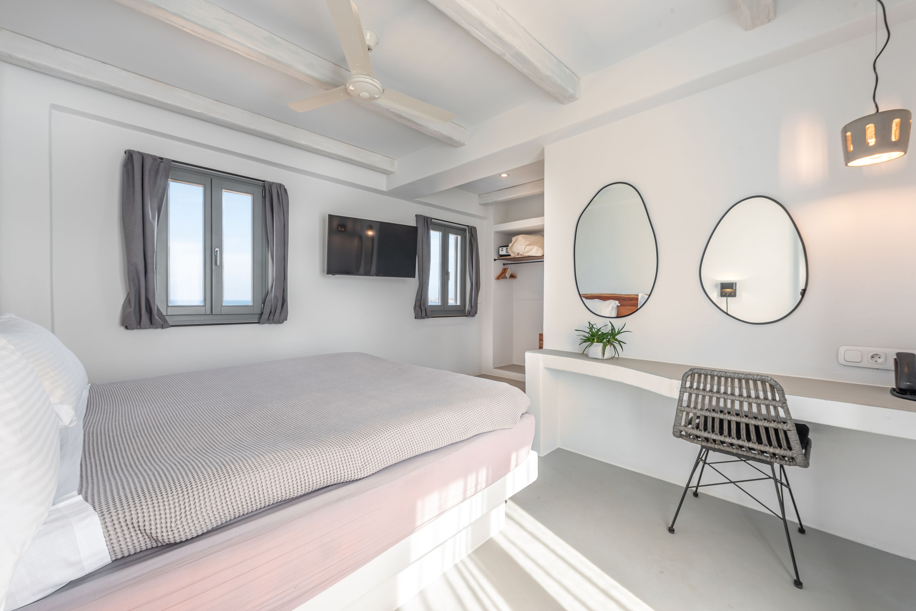 Un dormitorio moderno con cama, escritorio y dos espejos.