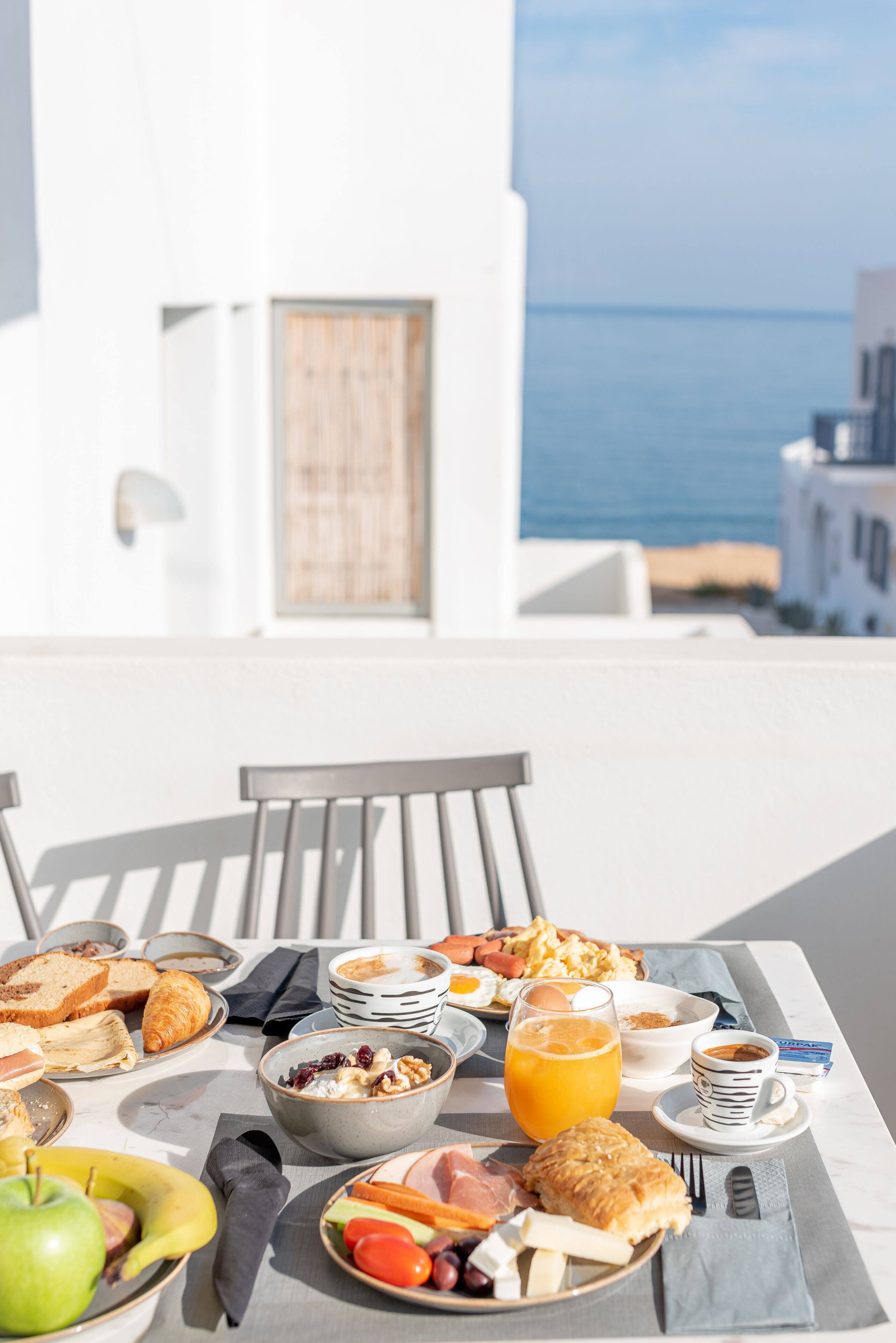 Ett frukostbord med olika sorters mat och dryck, med utsikt över havet.