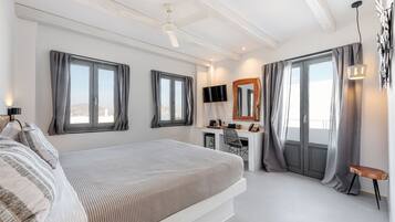 Quarto com cama, escrivaninha, cadeira e janelas amplas.