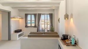 Una habitación moderna y bien iluminada con un sofá, una mesita y vista al mar.