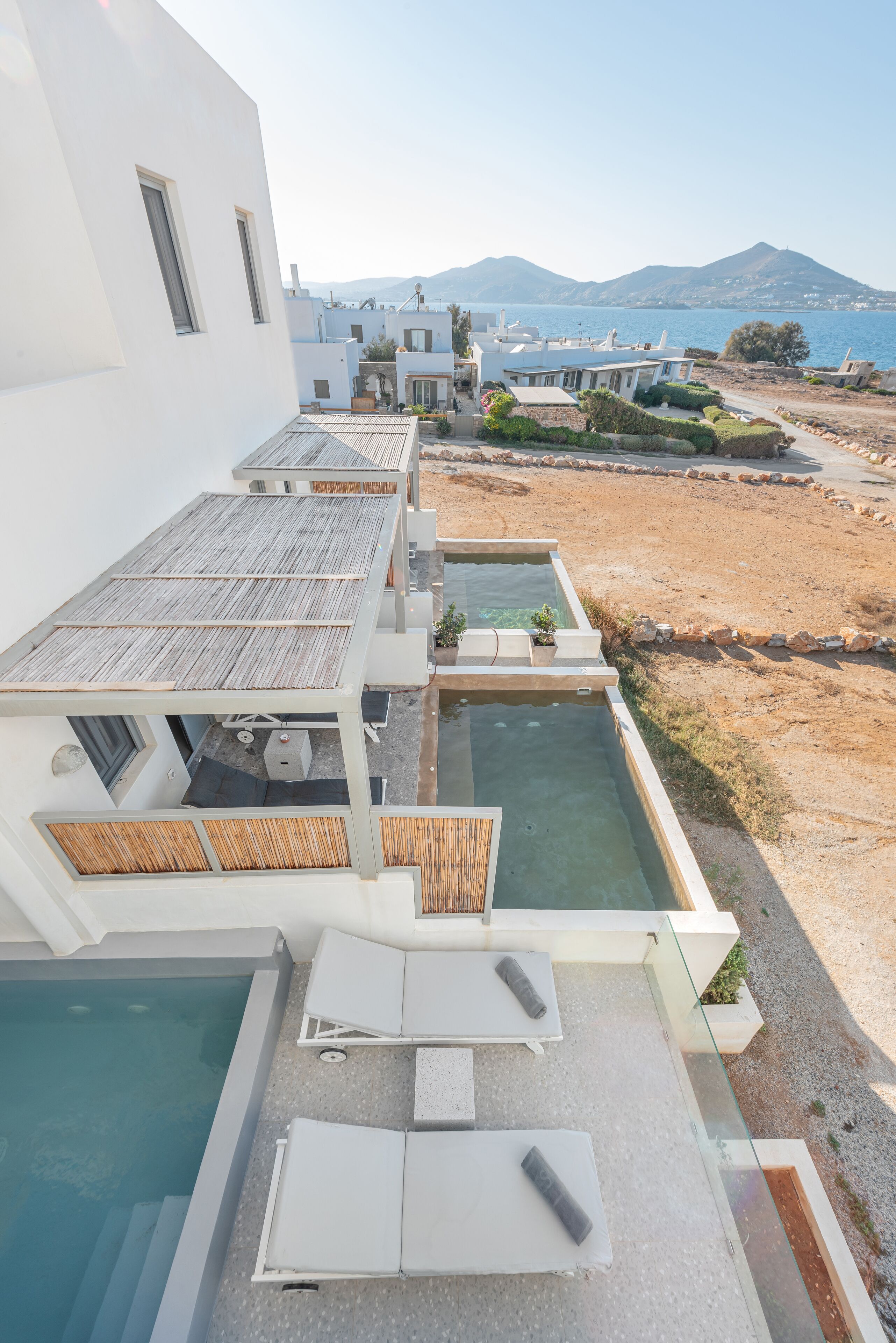 A modern hotel with a rooftop pool area, including lounge chairs and a small hot tub.