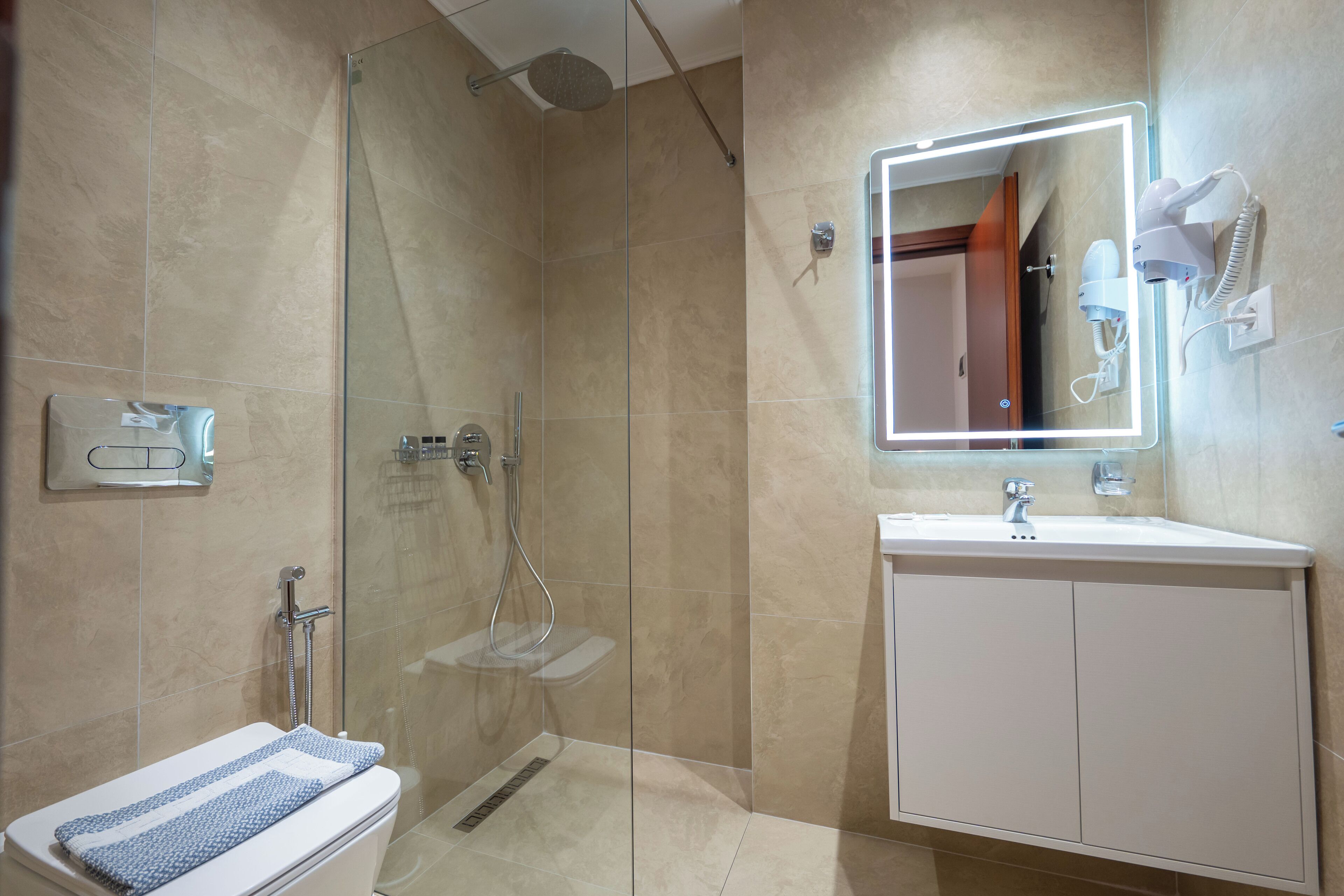 A modern bathroom with a glass-enclosed shower, a white sink with a mirror, and a towel rack.