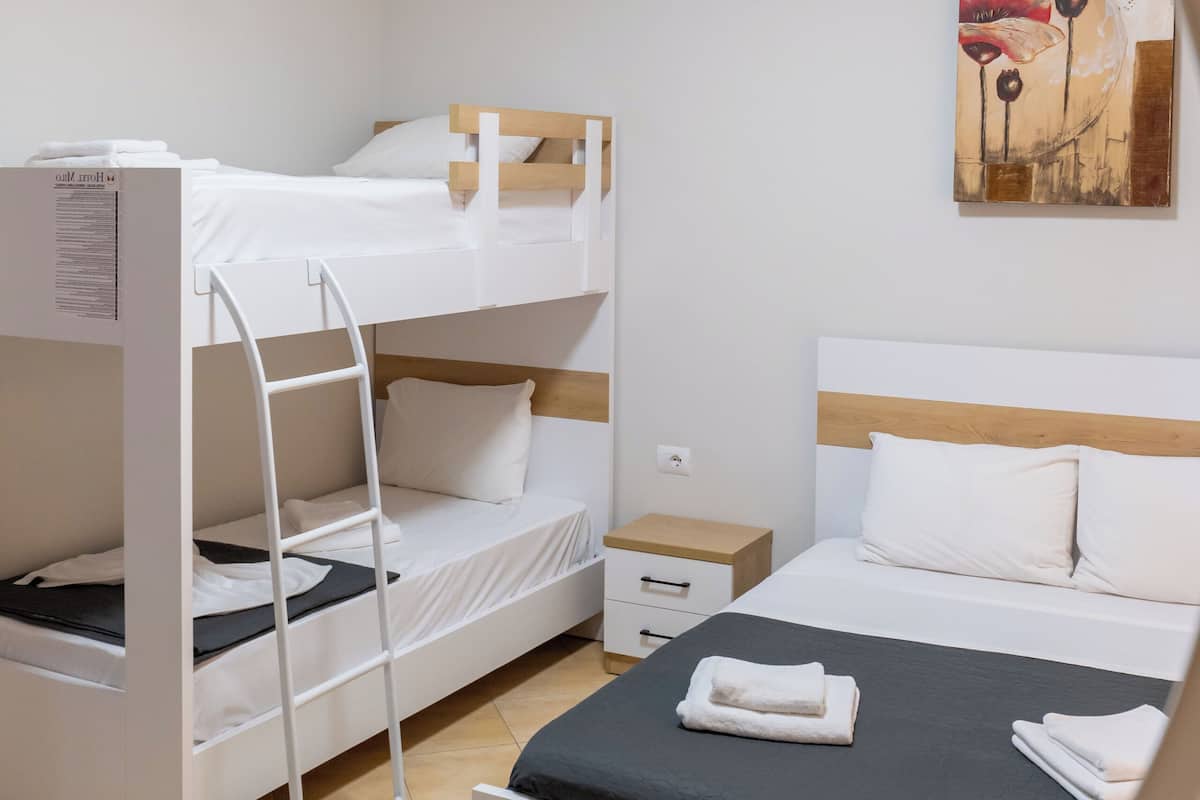 A bunk bed room with a ladder, a desk, and a bed with a black mattress.