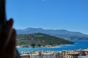 A coastal town with buildings overlooking a beach and mountains in the background.