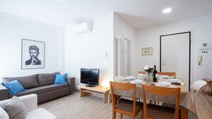 A modern living room with a sofa, TV, dining table, and chairs. - Anne Loren Al Mare (Alassio)