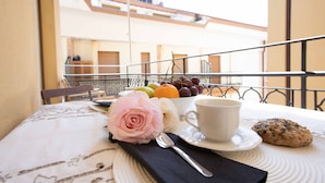 A balcony table with a fruit bowl, a cup, a cookie, and a rose. - Anne Loren Al Mare (Alassio)