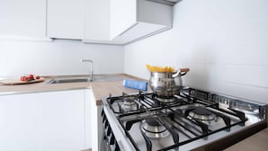 A modern kitchen with white cabinets, a stainless steel stove, and a pot of spaghetti. - Anne Loren Al Mare (Alassio)