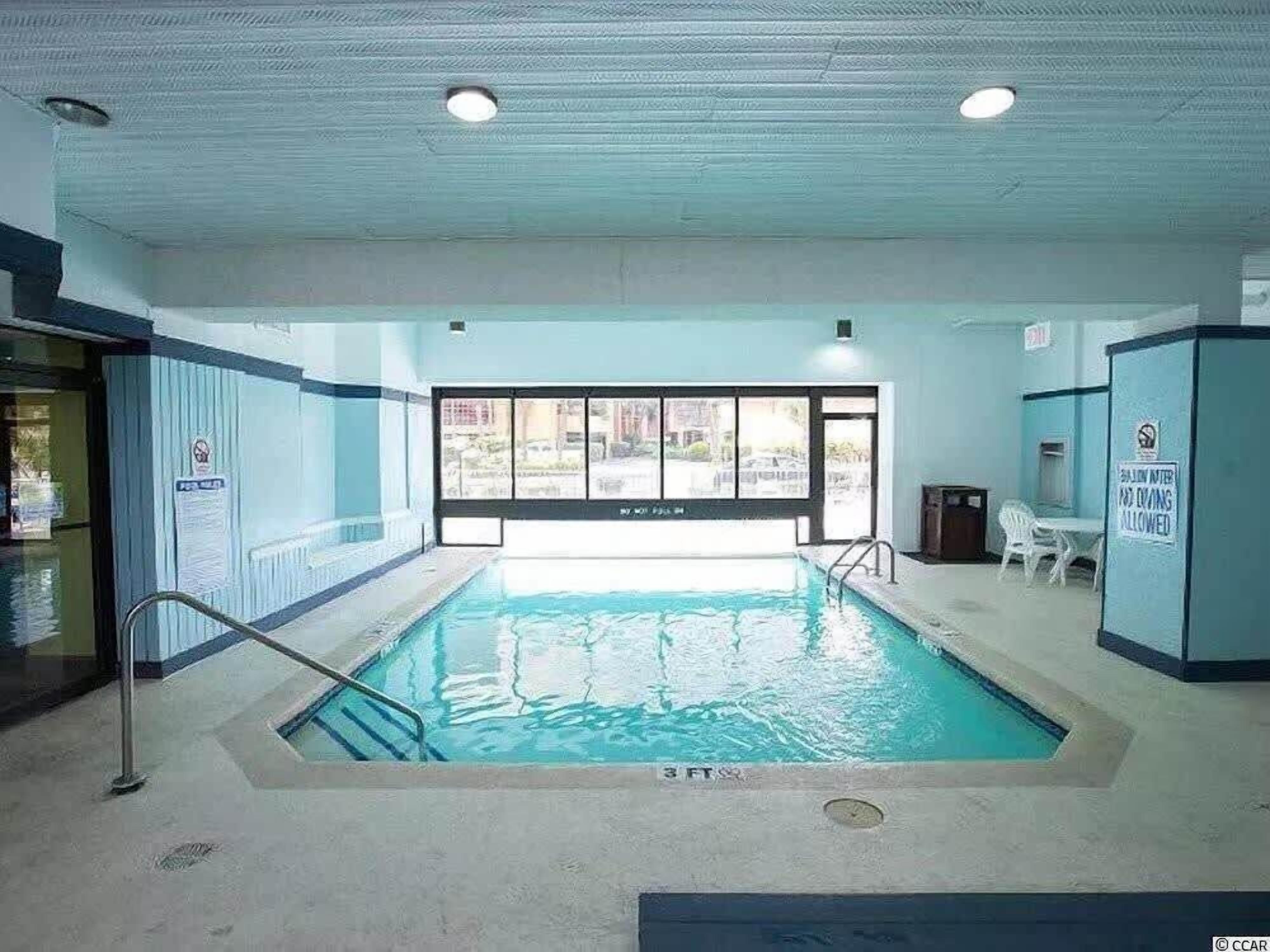Una piscina interior amb aigua cristal·lina, una escala metàl·lica i un cartell que indica que no es pot fer immersió.