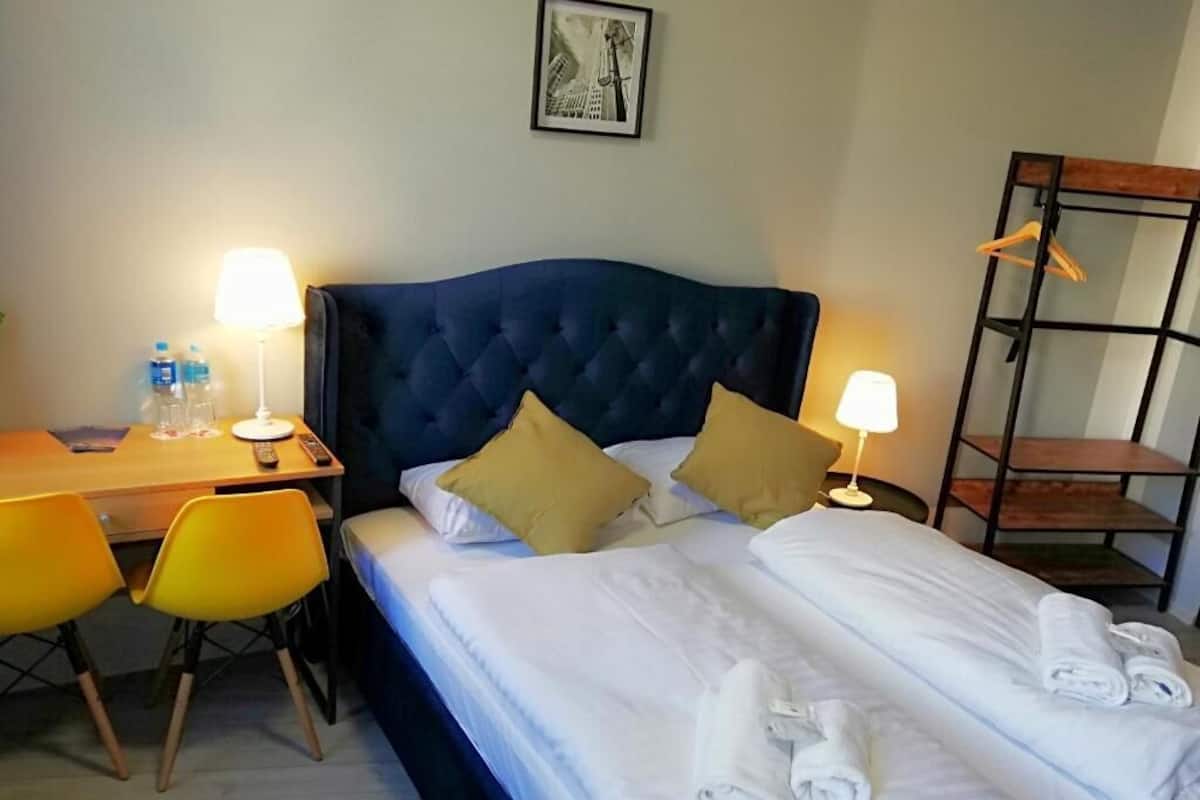 Une chambre d’hôtel avec un grand lit, deux lampes de chevet, un bureau avec une chaise et une étagère en bois.