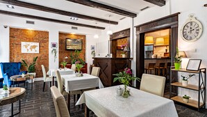 Ein Restaurant mit Ziegelwänden, Holzbalken und gedeckten Tischen.
