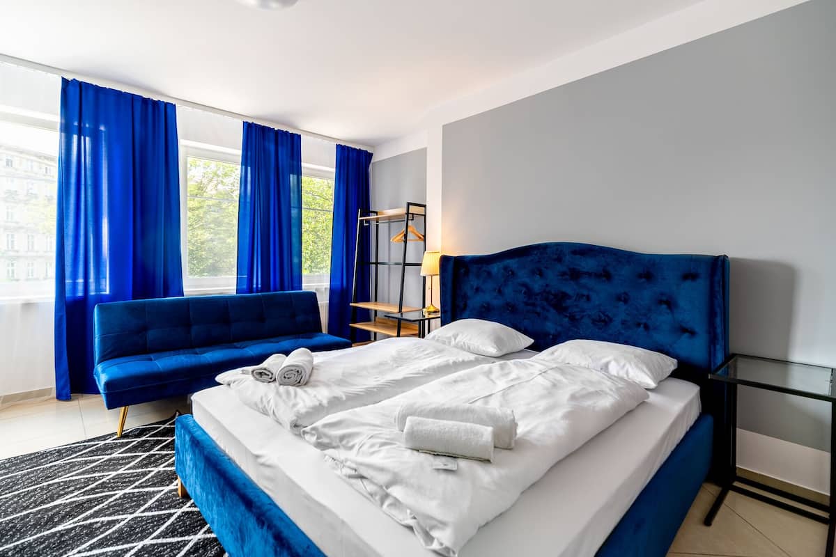 Une chambre d’hôtel moderne avec un grand lit, un canapé bleu et une table en verre.