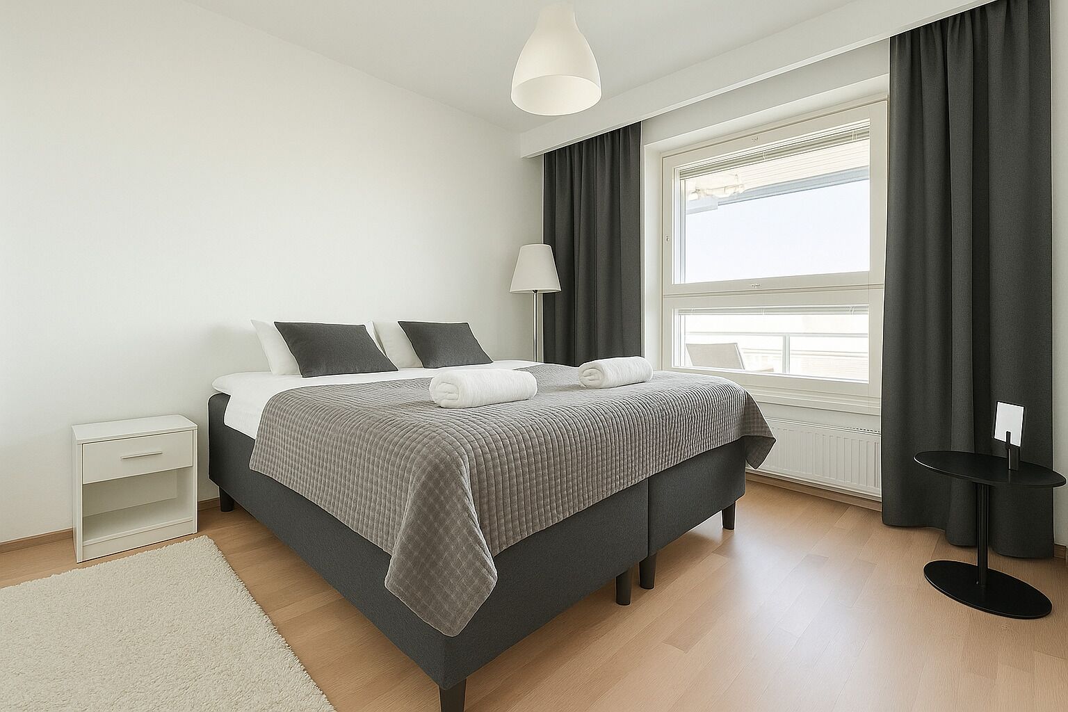 Un dormitorio moderno con cama, mesita de noche, lámpara y vistas al exterior.