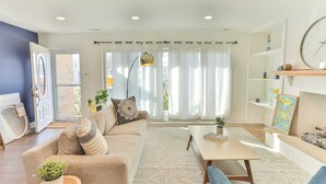 A modern living room with a sofa, coffee table, and a large window with curtains.