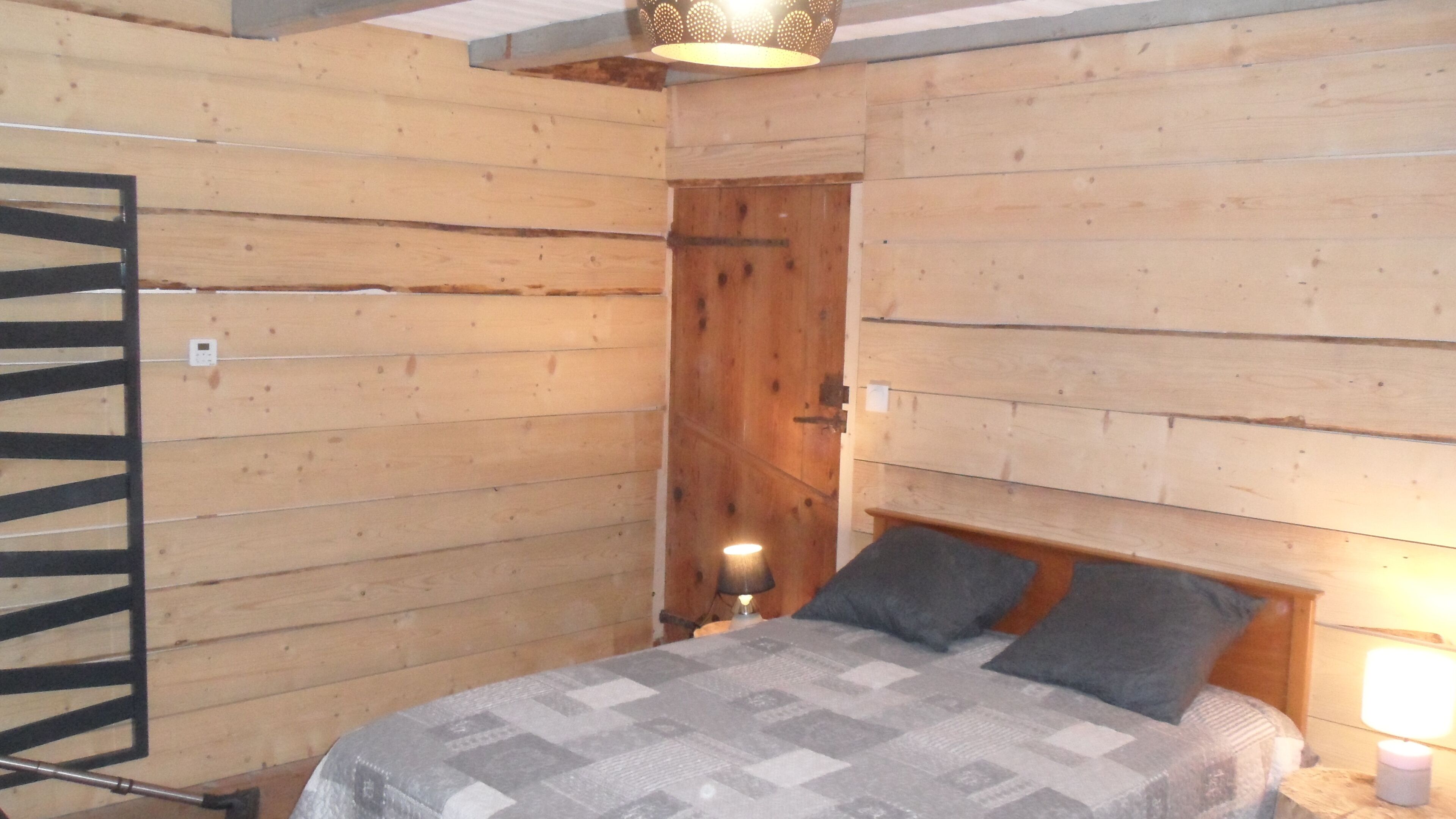 Una habitación de madera con una cama, una mesita de noche y una puerta.