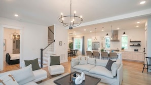 A spacious living room with a large chandelier, a sofa set, and a coffee table.