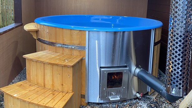 A hot tub with a blue rim, wooden steps, and a metal heater. - Lovely 1-bed House in Fochabers, Scotland (Fochabers)