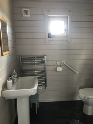 A bathroom with a white sink, a mirror, a window, a towel rack, and a toilet. - Lovely 1-bed House in Fochabers, Scotland (Fochabers)
