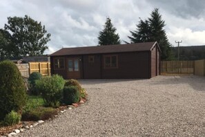 A single-story building with a gravel driveway and a fenced yard. - Lovely 1-bed House in Fochabers, Scotland (Fochabers)