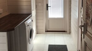 A laundry room with a washing machine, a door with a window, and a dark mat leading to the door. - Lovely 1-bed House in Fochabers, Scotland (Fochabers)