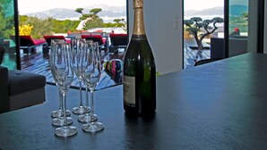 Eine Champagnerflasche und vier Gläser auf einem Tisch mit Blick auf einen Pool und Sitzgelegenheiten im Freien.