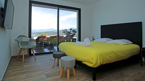 Ein Schlafzimmer mit Bett, Stuhl, Hocker und Blick ins Freie.