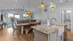 A spacious kitchen with a large island, pendant lights, and a dining area with a view.