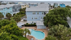 A residential area with a swimming pool, multiple houses, and a view of the ocean.