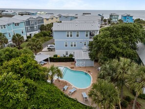 A residential area with a swimming pool surrounded by palm trees and a view of the ocean.