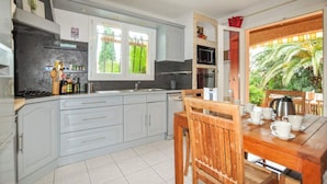 Una cocina con armarios grises, una mesa de comedor de madera y vistas al exterior.